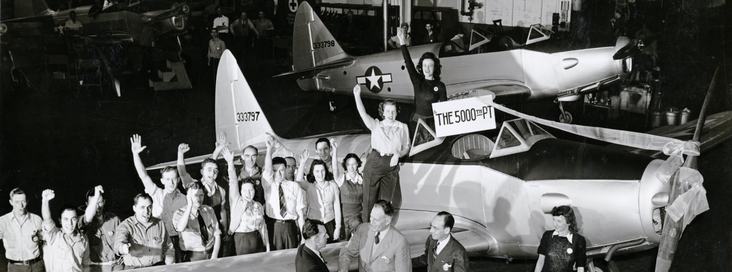 old picture of 5000th PT aircraft with workers waving